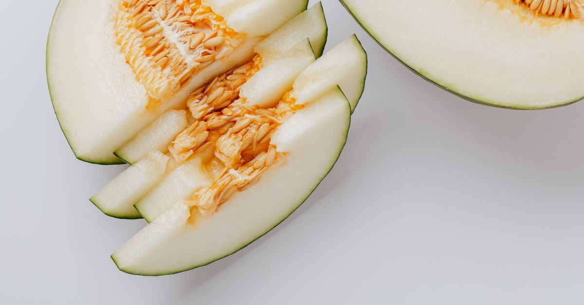 Pies wąchający kawałek pomarańczowego melona na drewnianej desce